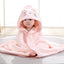 Child wearing a pink hooded towel with cat ears and a nose on a light background